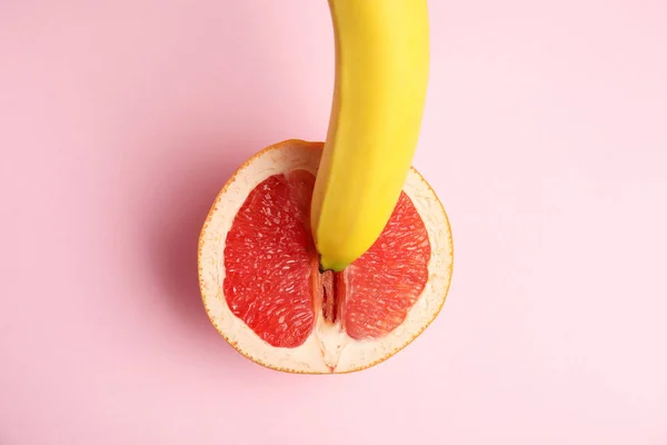 Pompelmo fresco e banana su sfondo rosa, vista dall'alto. Concetto sessuale — Foto Stock
