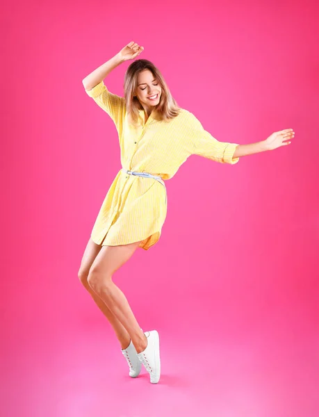 Pembe arka planda dans sarı elbiseli güzel genç kadın — Stok fotoğraf
