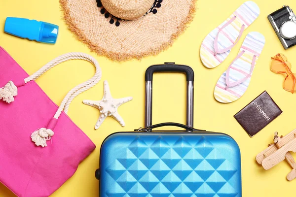 Flat lay composition with suitcase and beach objects on yellow background — Stock Photo, Image