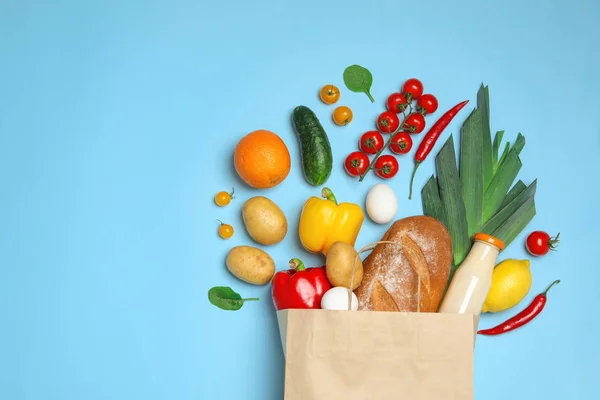 水色の背景に異なる食料品を持つショッピングペーパーバッグ、フラットレイ。テキスト用のスペース — ストック写真