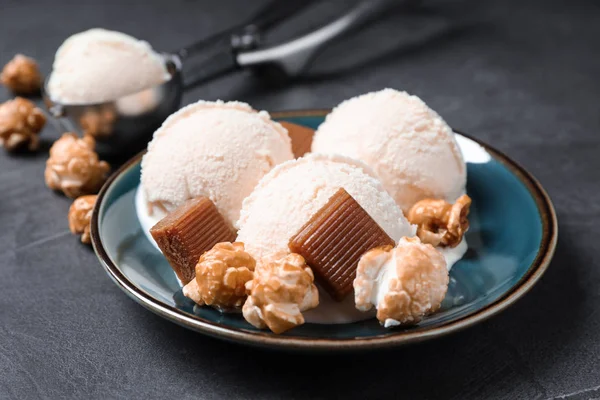 Тарелка мороженого с карамельными конфетами и попкорном на сером столе — стоковое фото