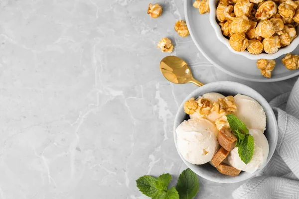 Skål med läcker glass med karamellgodis, popcorn och mynta på ljusgrå marmorbord, Flat Lay. Utrymme för text — Stockfoto