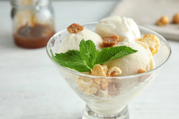 Delicioso sorvete com doces de caramelo e pipoca em tigela de sobremesa na mesa branca, close-up — Fotografia de Stock