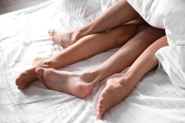 Passionate young couple having sex on bed, closeup of legs — Stock Photo, Image