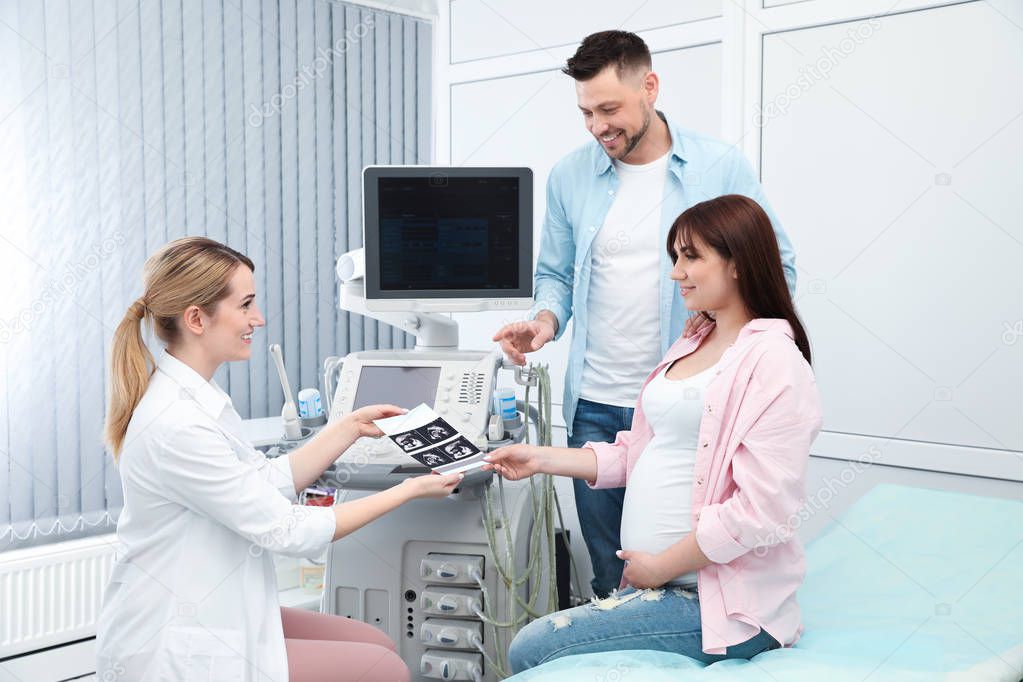 Doctor showing ultrasound of baby to future parents in clinic