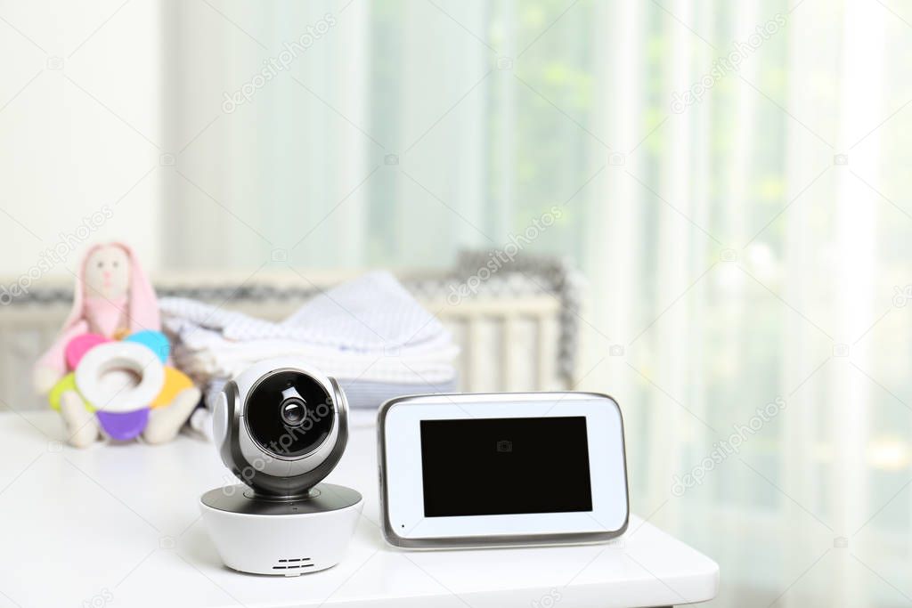 Baby monitor with camera and accessories on table in room. Video nanny