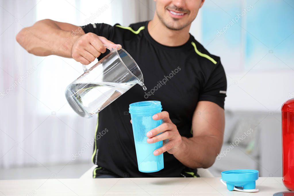 Young athletic man preparing protein shake at home, closeup view