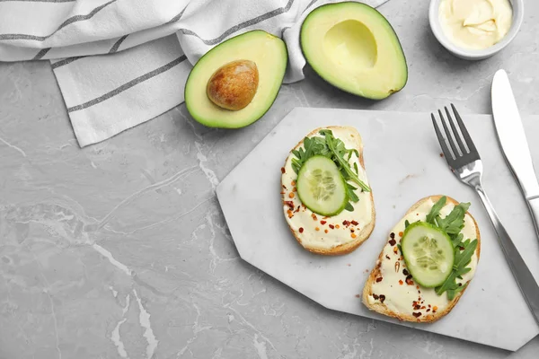 Schijfjes brood met sprei en komkommer op grijs marmeren tafel, platte lay — Stockfoto