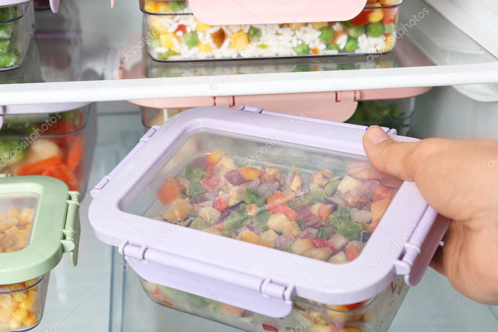 Woman taking box with vegetable mix from refrigerator, closeup