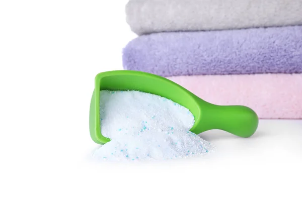 Laundry detergent in plastic measuring scoop and towels on white background — Stock Photo, Image