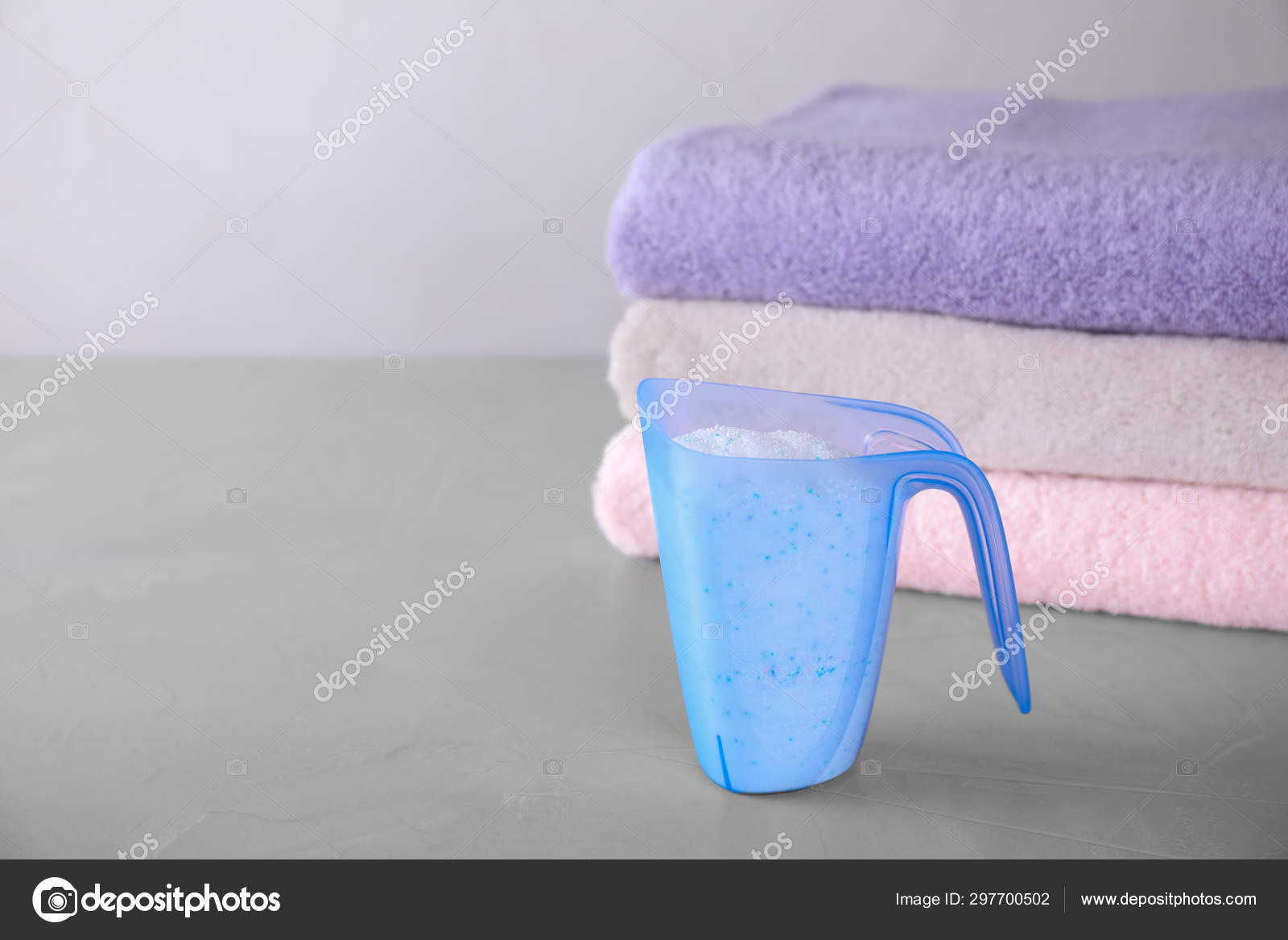 Measuring cup of laundry powder and clean towels on grey table against  light background. Space for text Stock Photo by ©NewAfrica 297700502