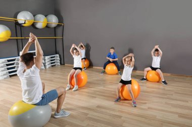 Sevimli küçük çocuklar ve eğitmen okul spor salonunda fiziksel egzersiz yapıyor. Sağlıklı yaşam tarzı