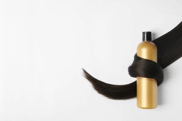 Пляшка шампуню, загорнута в замок волосся, ізольована на білому, вид зверху. Натуральні косметичні продукти — стокове фото
