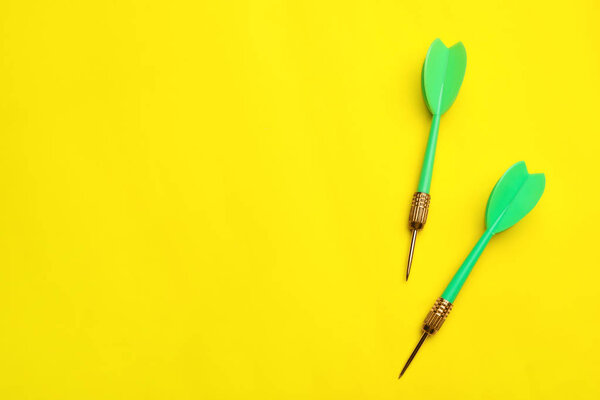 Зеленый дротик стрелки на желтом фоне, плоский лежал с пространством для текста
