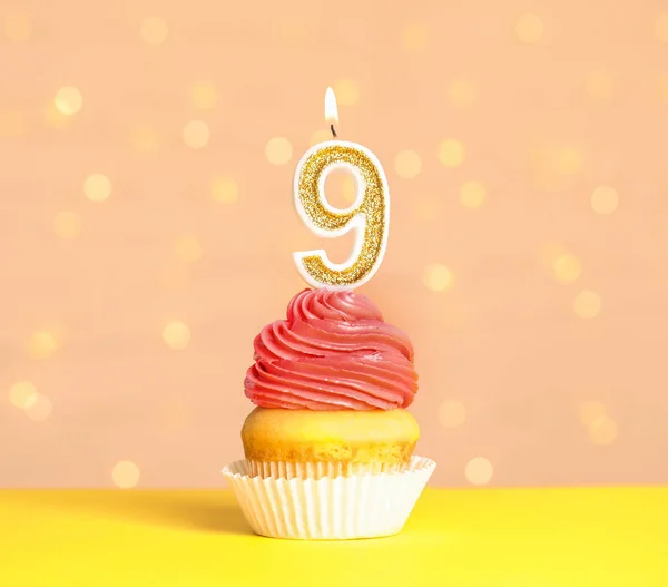 Cupcake d'anniversaire avec numéro neuf bougie sur la table contre les lumières festives — Photo