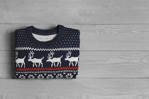 Warm folded Christmas sweater on grey wooden table, top view. Space for text — Stock Photo, Image