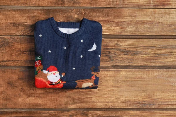 Warm folded Christmas sweater on wooden table, top view. Space for text — Stock Photo, Image