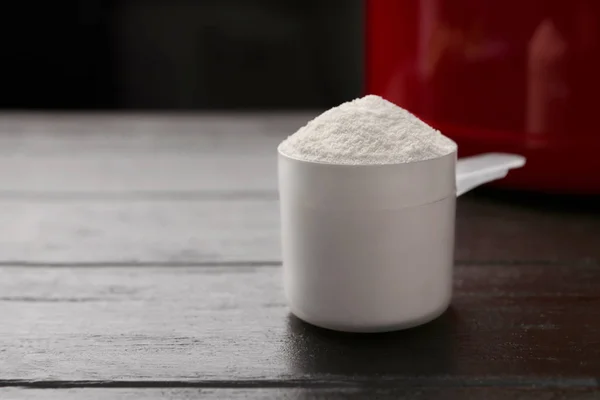 Medindo colher de proteína em pó na mesa de madeira escura, close-up. Espaço para texto — Fotografia de Stock