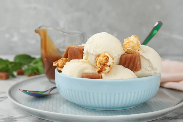 Piatto di delizioso gelato con caramelle al caramello e popcorn in tavola — Foto Stock