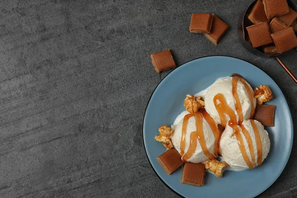 Delizioso gelato con guarnizione al caramello sulla tavola grigia, posa piatta. Spazio per testo — Foto Stock