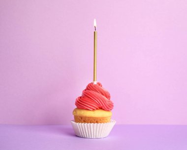 Mor arka plan üzerinde mum ile Doğum günü cupcake