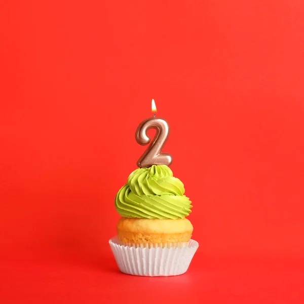 Cupcake di compleanno con candela numero due su sfondo rosso — Foto Stock