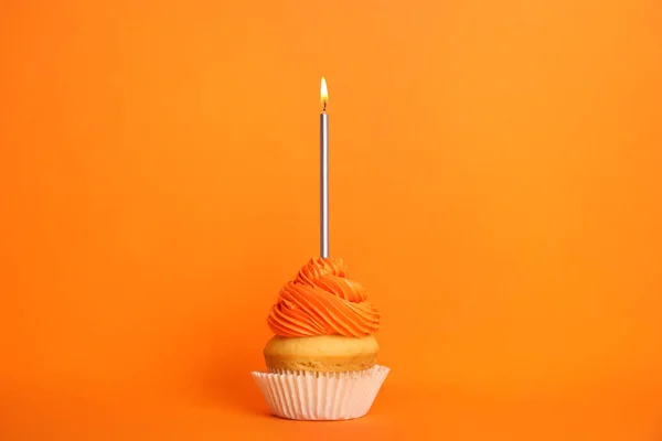 Birthday cupcake with candle on orange background