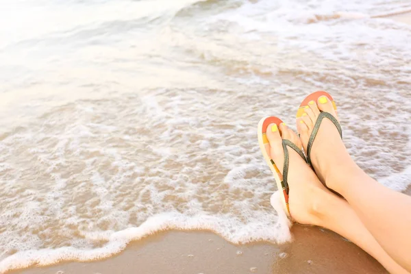 Gros plan de la femme avec des tongs élégantes sur le sable près de la mer, espace pour le texte. Accessoires de plage — Photo