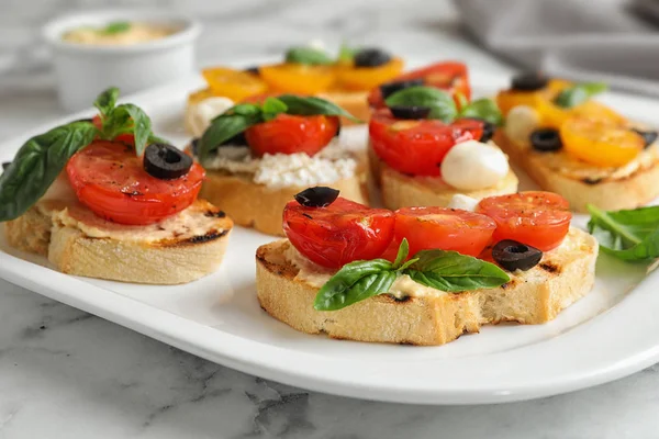 Plate of delicious tomato bruschettas on white marble table, closeup — Stock Photo, Image