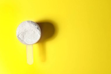 Sarı arka planda protein tozu kepçesi, metin için alan la üst görünüm