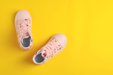 Sarı arka plan üzerinde şık çocuk ayakkabıları çifti, düz yatıyordu. Metin için alan