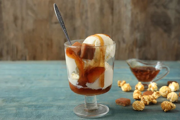 Delizioso gelato con guarnizione caramello nella ciotola del dessert sul tavolo di legno blu — Foto Stock