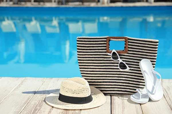 Accesorios de playa en la cubierta de madera cerca de la piscina al aire libre, espacio para texto —  Fotos de Stock