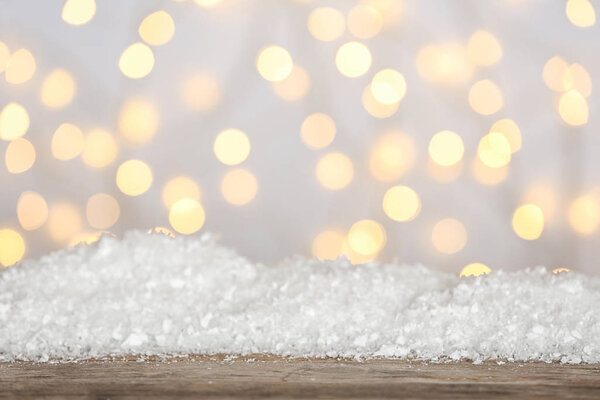 Heap of snow on wooden surface against blurred background. Christmas season