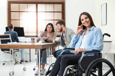 Ofiste meslektaşları ile tekerlekli sandalyede genç kadın