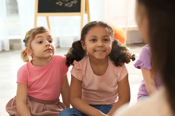 Crianças pequenas bonitos ouvir professor dentro de casa. Atividades lúdicas do jardim de infância — Fotografia de Stock
