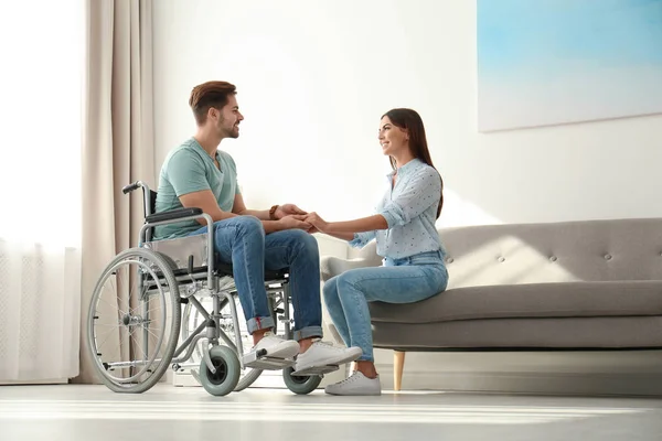 Молодая женщина с мужчиной в инвалидной коляске в помещении — стоковое фото
