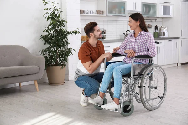 Jonge man met vrouw in rolstoel binnenshuis — Stockfoto