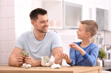 Evde kırık kumbara ve para ile aile