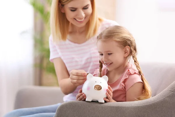Família com banco porquinho e dinheiro em casa — Fotografia de Stock
