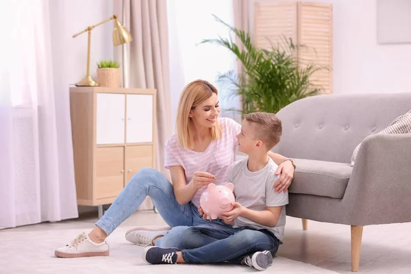 Familia con alcancía y dinero en casa. Espacio para texto —  Fotos de Stock