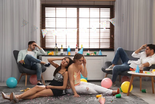 Grupo de amigos que sufren de resaca en la habitación desordenada después de la fiesta —  Fotos de Stock