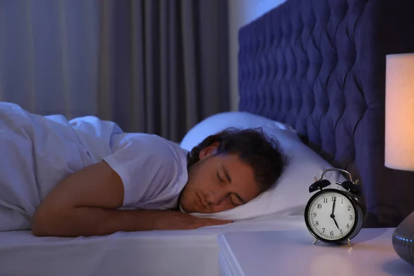 Красивый молодой человек спит на подушке по ночам. Время спать — стоковое фото