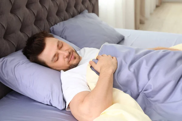 Un bel homme dormant sur un oreiller à la maison. Au lit. — Photo