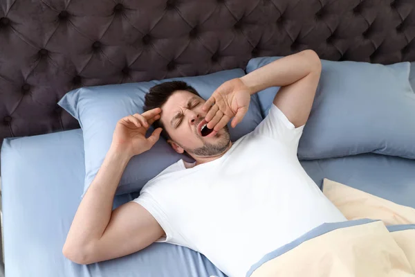 Hombre guapo bostezando mientras está acostado en la almohada, vista desde arriba. Hora de dormir —  Fotos de Stock