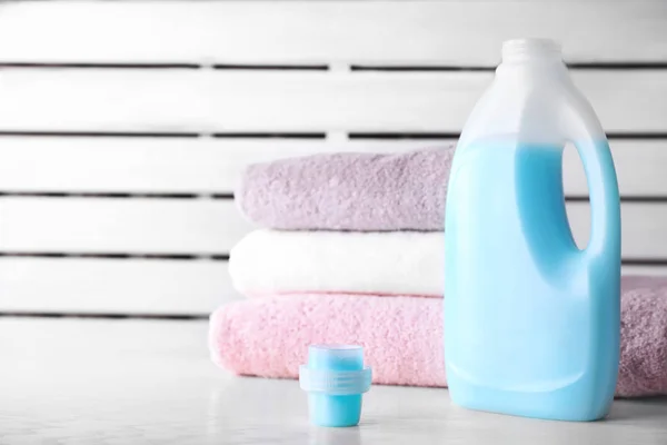 Waschmittel und saubere Handtücher auf dem Tisch vor verschwommenem Hintergrund. Raum für Text — Stockfoto