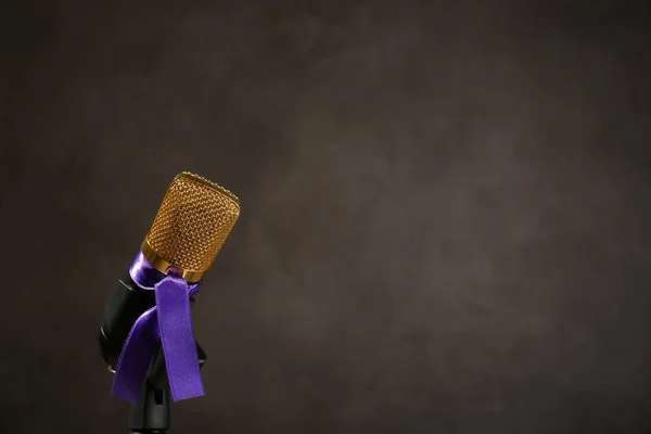 Microphone with purple awareness ribbon on dark background, space for text