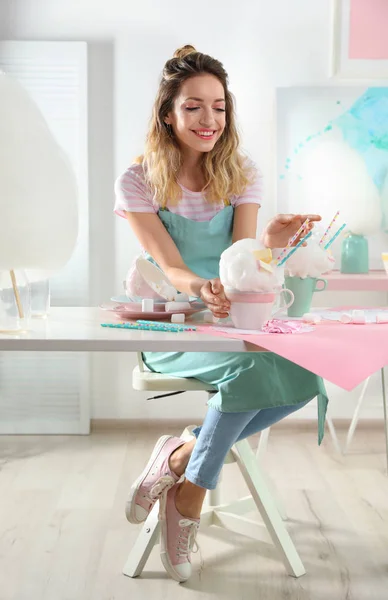 Jovem com xícara de algodão doce sobremesa à mesa no quarto — Fotografia de Stock