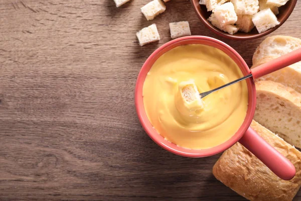 Flat Lay sammansättning med potten av ostfondue och bröd på träbord, utrymme för text — Stockfoto