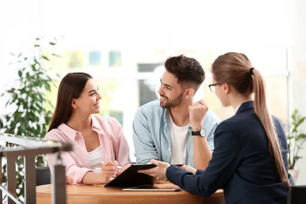 Agente de seguros femenino que trabaja con parejas jóvenes en el cargo — Foto de Stock